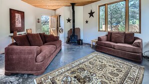 A spacious living room with two brown sofas, a large rug, and a wood-burning stove.