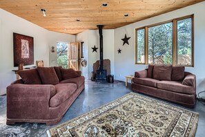 A spacious living room with two brown sofas, a large rug, and a wood-burning stove.