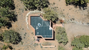 An aerial view of a property with a large, enclosed patio area, surrounded by natural vegetation and a stone wall.