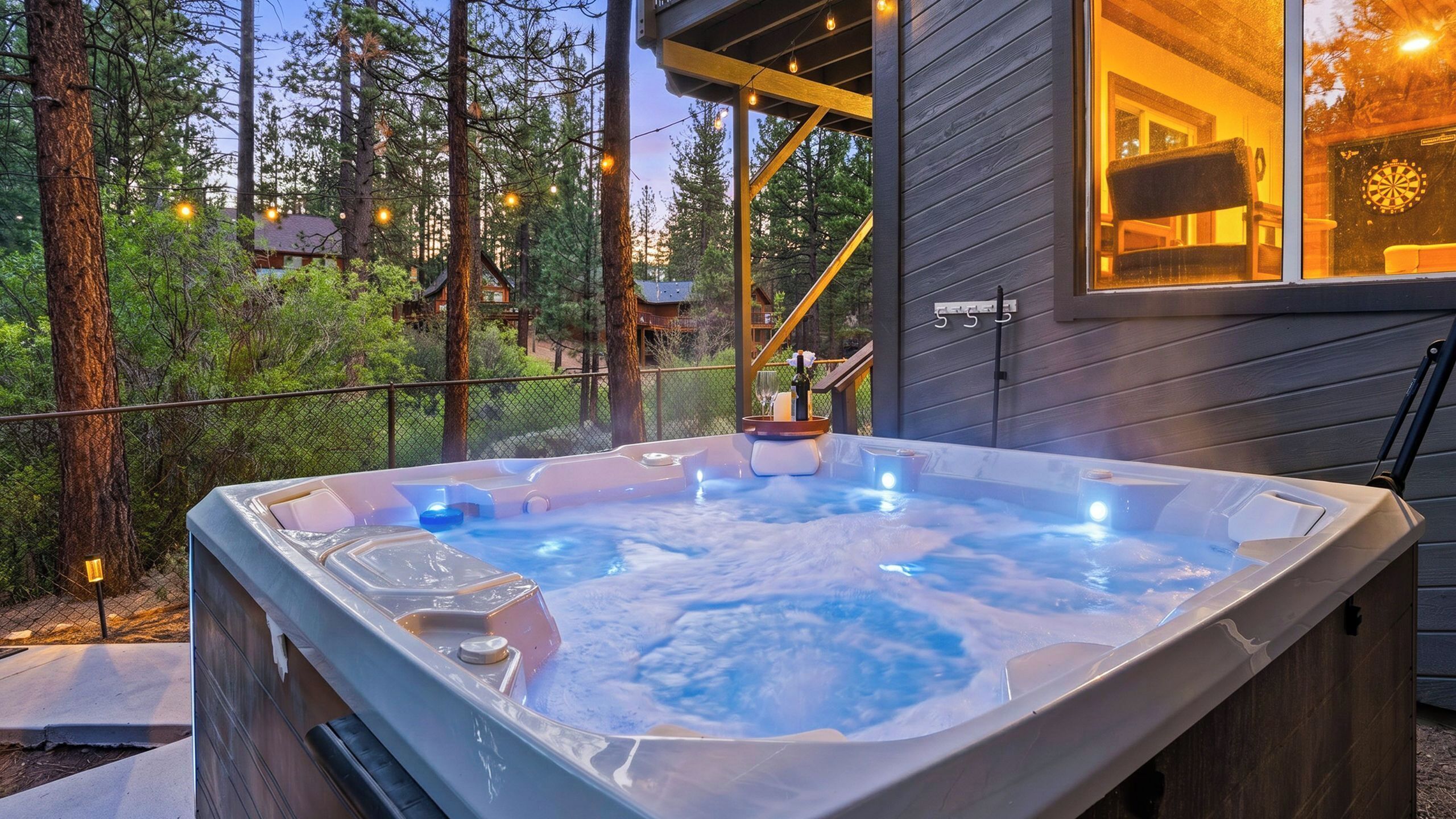 Un bain à remous avec une terrasse en bois, entouré d’arbres et situé près d’une maison sur laquelle on peut clairement voir le numéro « 555 ».