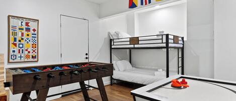 Una cama litera, una mesa de futbolín y otra mesa de futbolín con portería.