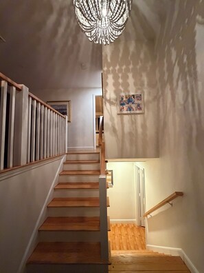 Eine Treppe mit Holzboden und einer weißen Geländer, das zu einem Raum mit einem Kronleuchter führt.