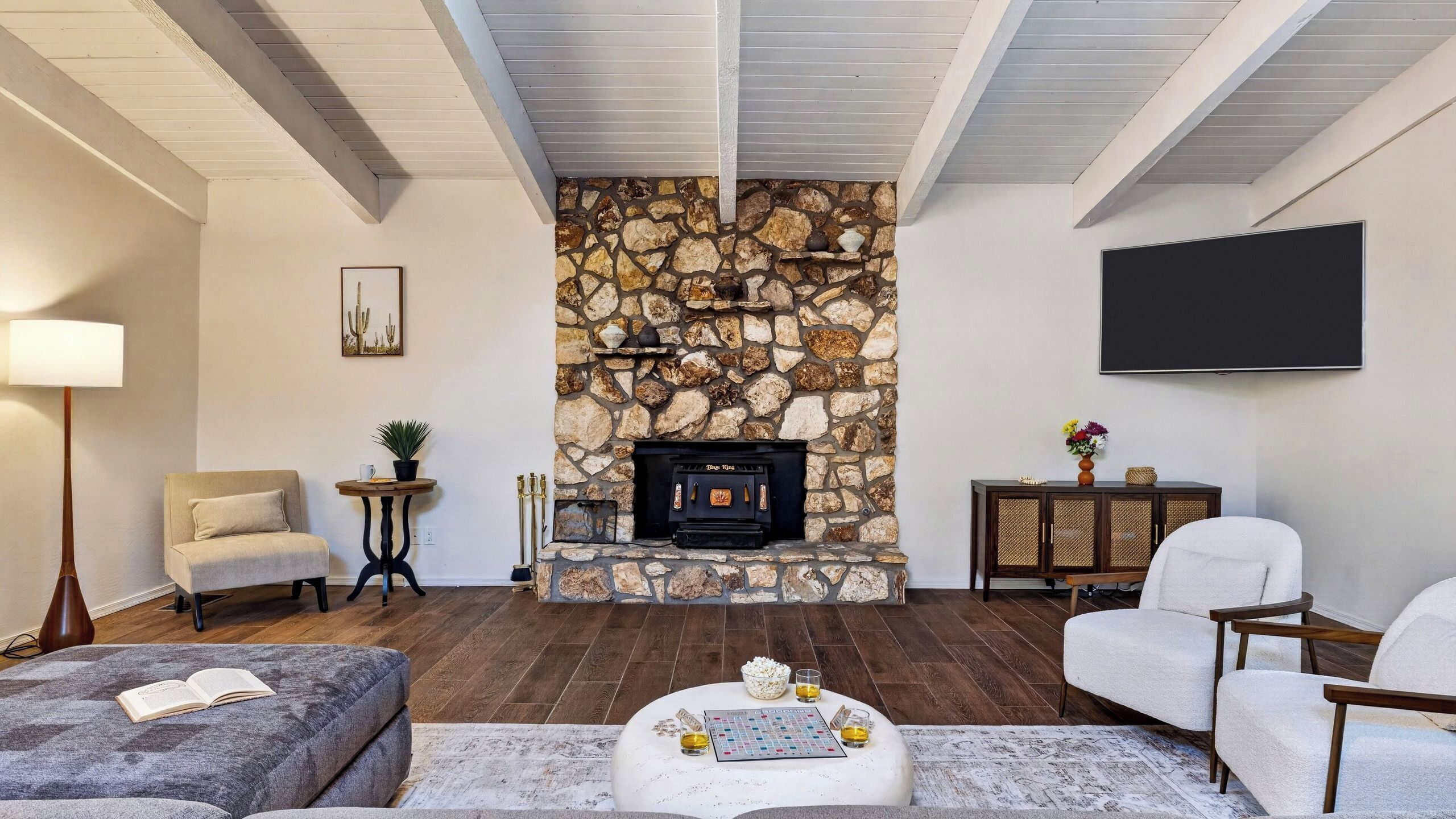 Una sala de estar con chimenea de piedra, un televisor de pantalla plana y un rincón de descanso acogedor.