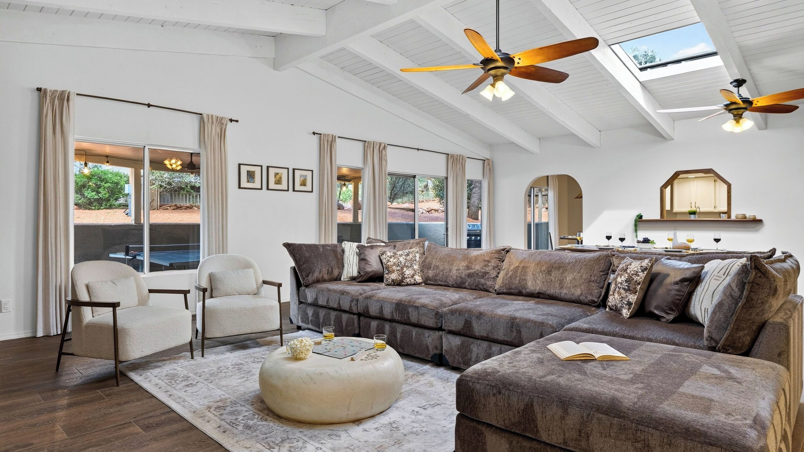 Ein großzügiges Wohnzimmer mit einer großen Couch, einem runden Couchtisch und einem Deckenventilator.