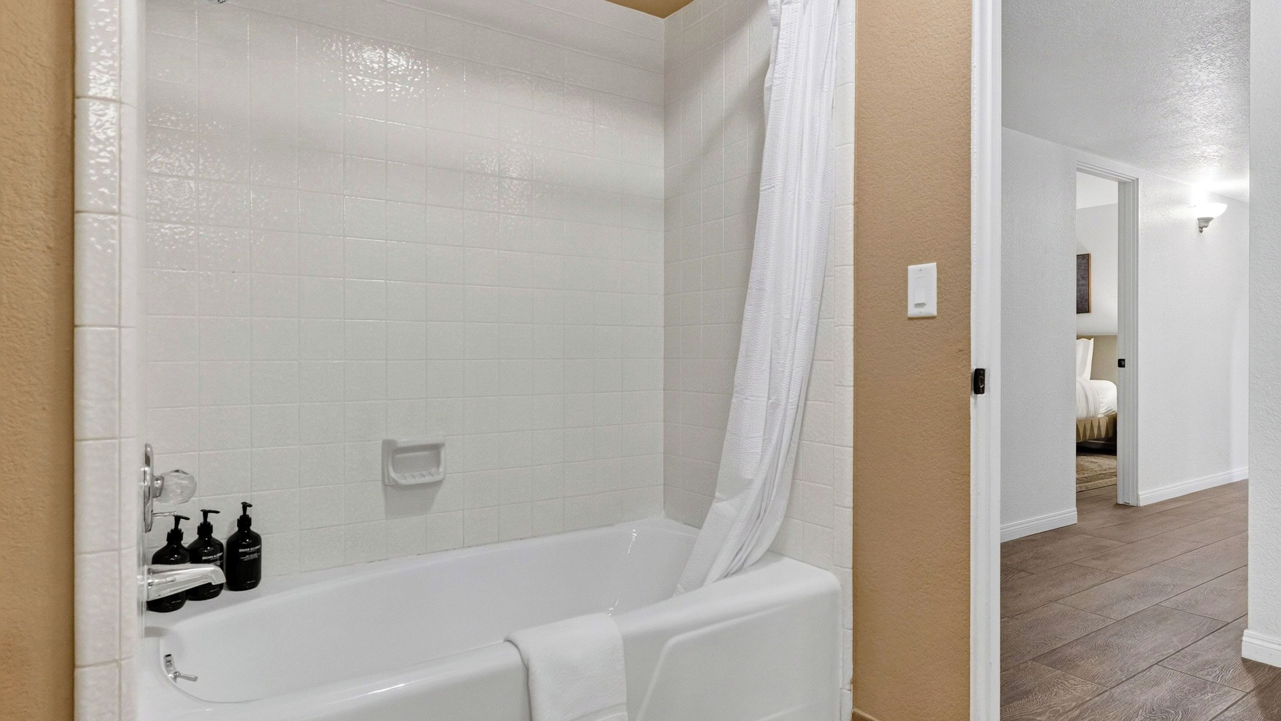 A bathroom with a bathtub, a shower curtain, and a toilet.