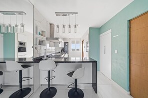 Une cuisine moderne dotée d’un îlot central, de luminaires suspendus et de tabourets de bar.