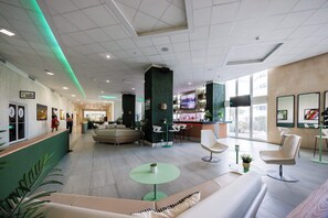 A modern hotel lobby with a reception desk, seating area, and a bar. - ESJ Towers Studio Isla Verde with Queen Beds (isla verde)