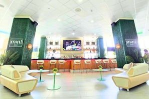 A bar area with a counter, seating, and a TV screen. - ESJ Towers Studio Isla Verde with Queen Beds (isla verde)