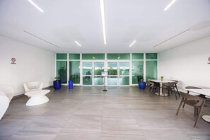 A spacious, modern office with a large glass door entrance, white walls, and a mix of white and brown furniture. - ESJ Towers Studio- Beach Access (isla verde)