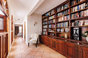 Inviting hallway library with rich wooden shelves, warm lighting, and vintage charm — a perfect reading nook that captures the elegance of Old San Juan. - Old San Juan 2 BR Apt with Queen Beds and Sofabeds (SanJuan)