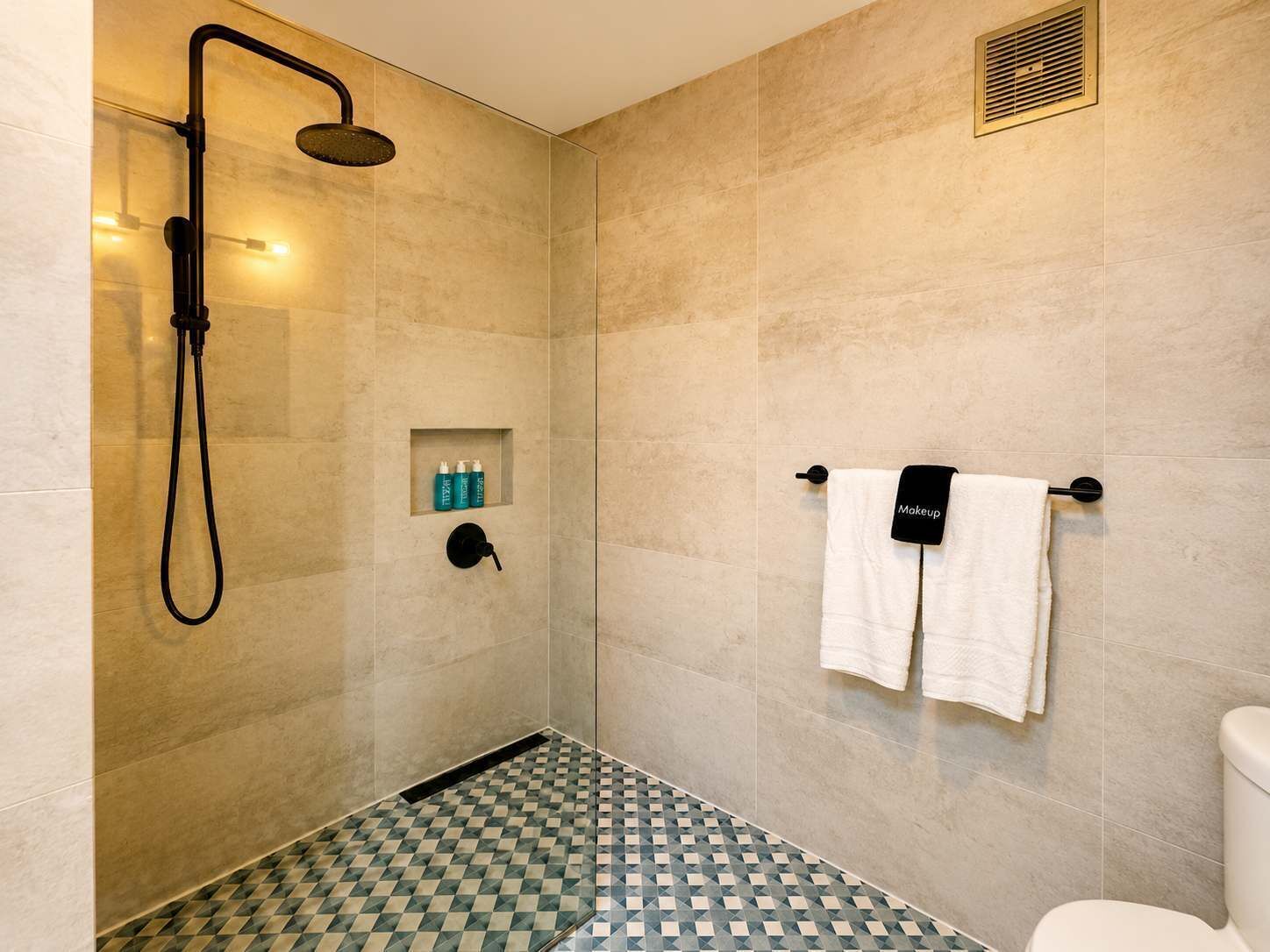 Une salle de bain avec une douche, des toilettes et un porte-serviettes.
