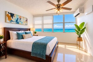 Ein Schlafzimmer mit einem großen Bett, einem Deckenventilator, einem Fenster mit Meerblick und einem Bild an der Wand.