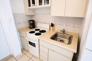 A compact kitchen with a stove, oven, sink, and a coffee maker. - Queen Bed in Coral Beach Apartment Isla Verde (Avenida Isla)