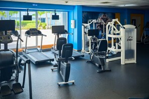 A gym with treadmills, elliptical machines, and weight machines. - Queen Bed in Coral Beach Apartment Isla Verde (Avenida Isla)