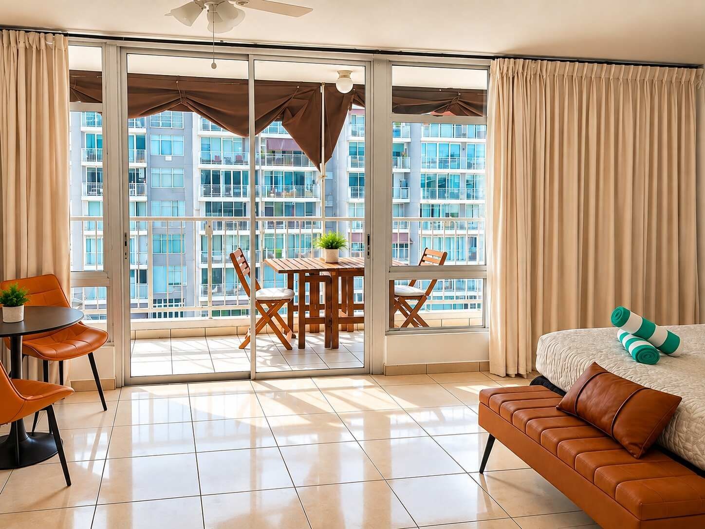 A modern hotel room with a balcony, a dining table, and a sofa.