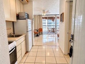 A modern kitchen with a refrigerator, stove, and sink. - Queen Bed in Coral Beach Apartment Isla Verde (Avenida Isla)