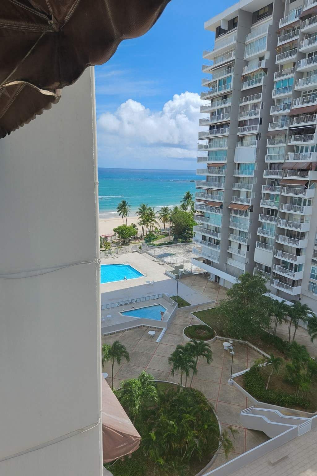 Un edificio alto con varios balcones que dan a una playa y a una zona de piscina.