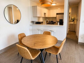 Eine moderne Küche mit einem runden Holztisch, vier Stühlen, einer Hängelampe und einem Spiegel an der Wand.