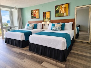 A hotel room with two beds, a balcony, and artwork on the walls. - Isla Verde ESJ Towers Studio Apt with Queen Beds (Avenida Isla)