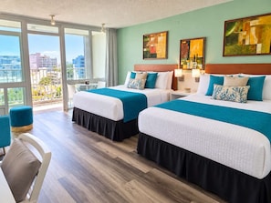 A hotel room with two beds, a balcony with a view, and artwork on the walls. - Isla Verde ESJ Towers Studio Apt with Queen Beds (Avenida Isla)