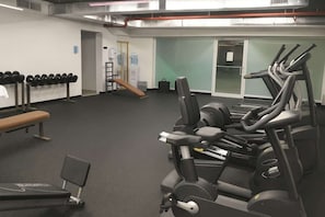 A gym with exercise equipment, a bench, and a water cooler. - Isla Verde ESJ Towers Studio Apt with Queen Beds (Avenida Isla)