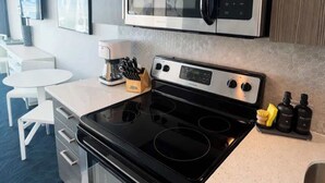 A modern kitchen with a black stove, a microwave, and a coffee maker. - ESJ Towers Studio - Walk to the Beach (Avenida Isla)