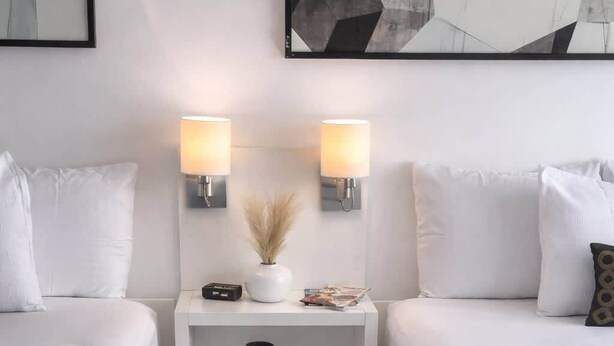A hotel room with two beds, a nightstand with lamps, a vase with dried flowers, and abstract wall art. - ESJ Towers Studio - Walk to the Beach (Avenida Isla)
