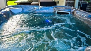 Ein Whirlpool mit Marmordesign, umgeben von einer Terrasse mit Gartenmöbeln.