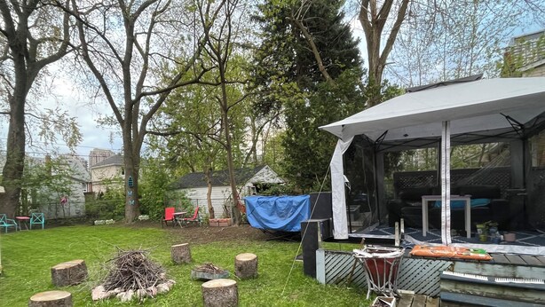 Un jardin avec un espace extérieur couvert, une terrasse en bois et un petit potager agrémenté de plantes en pot.