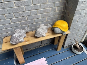 Un banc orné de trois sculptures d’animaux et un casque jaune, le tout adossé à un mur de briques.