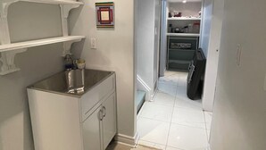 Un couloir étroit avec un coin cuisine sur la gauche, comprenant un évier, des placards et un plan de travail.