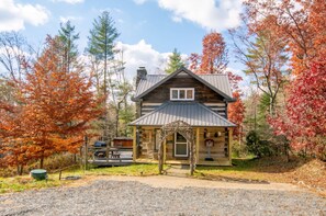 Eine rustikale Holzhütte mit Veranda, umgeben von Herbstlaub.