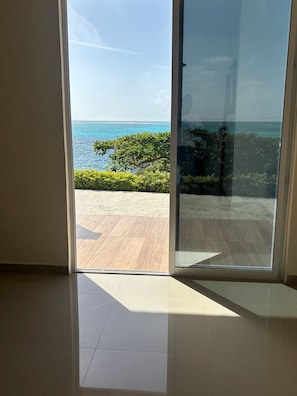 A room with a sliding glass door leading to a balcony with a view of the ocean and a clear sky. - Adorable 1-bedroom bed & breakfast with AC in Providence (Providence island)