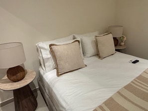 A hotel room with a bed, two bedside tables, and a lamp on each table.