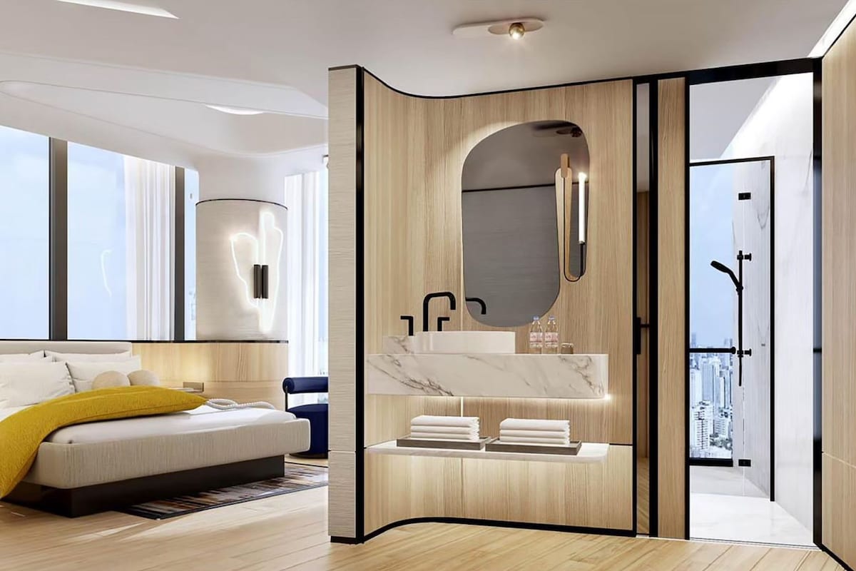Ein modernes Hotelzimmer mit Bett, Badezimmer mit Waschtisch und Blick auf die Stadt.