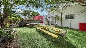 A backyard with a picnic table, chairs, and a red shed. - The Sunny 2-Bedroom Retreat | POOL (Miami)
