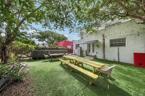 Ein Garten mit einem Picknicktisch, Stühlen und einem roten Schuppen.