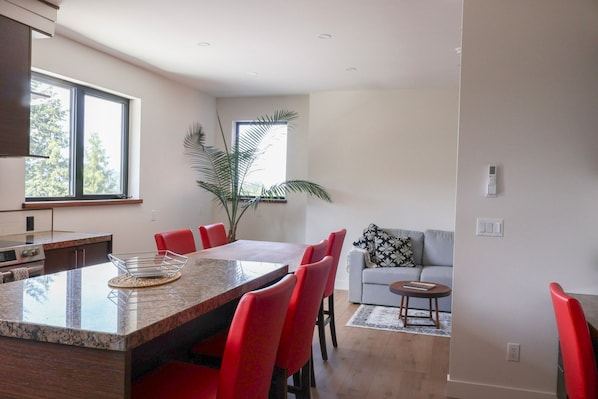 A modern kitchen with a large island, red chairs, and a dining table.