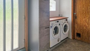 Een wasserette met twee wasmachines, een houten aanrecht en een deur.