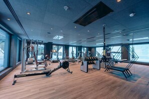 A gym with exercise equipment, large windows, and a wooden floor. - Alpin Lodge das Zillergrund (Mayrhofen)