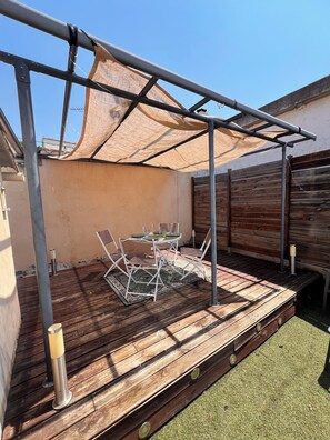 A wooden deck with a table and chairs, a pergola, and a wooden fence. - Charming, air-conditioned house near the highway and public transportation (Marseille)