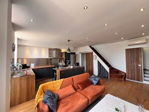 A modern kitchen with a central island, a sofa with cushions, and a staircase leading to another level. - Charming, air-conditioned house near the highway and public transportation (Marseille)