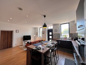A modern kitchen with a dining area, a TV, and a large window. - Charming, air-conditioned house near the highway and public transportation (Marseille)