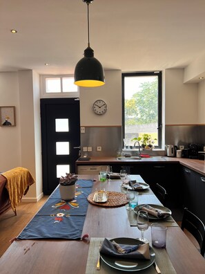 Eine moderne Küche mit Essbereich, einer Wanduhr und einem Fenster, das für natürliches Licht sorgt.