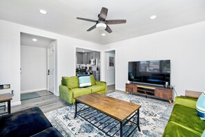 Una sala moderna con sofá, mesa de centro, televisor y ventilador de techo.