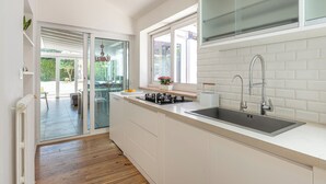 Een moderne keuken met een groot eiland, een ingebouwde gootsteen en een raam met uitzicht op een tuin.