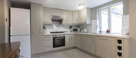 A kitchen with white cabinets, a built-in oven, a microwave, and a sink.