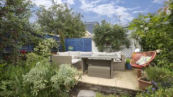 Eine Terrasse mit Korbmöbeln, einem roten Stuhl und Topfpflanzen.