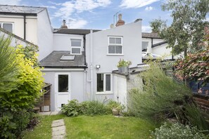 A residential property with a small garden, a pathway, and a white exterior. - Charming 3-Bedroom Home with Cosy Log Burner (Cheltenham)