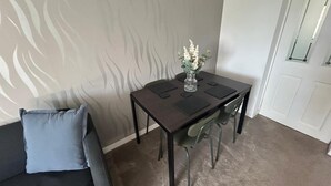 Un comedor con una mesa, sillas, un florero y un sofá gris.